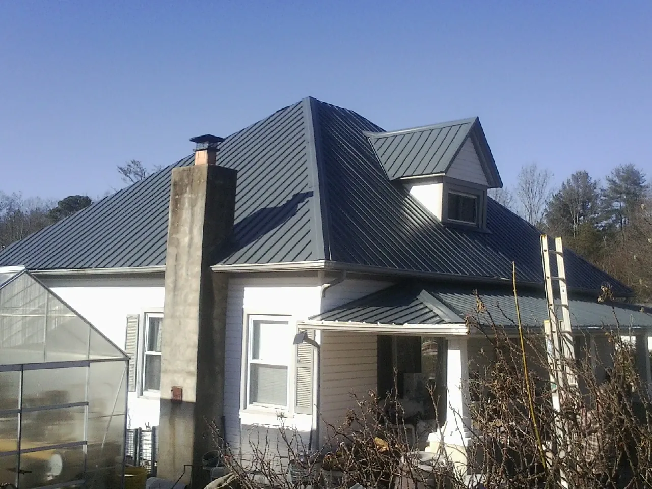 Dark blue standing seam metal roof on a white farmhouse with dormer — Slate & Tile Roof Repair by Roofing Brothers in Herminie