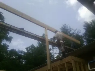 Carpenter setting a ridge beam over a new addition frame — Ice Dam Removal by Roofing Brothers in Herminie