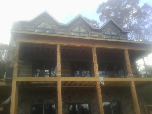 Dormers and porch framing on a large log home under construction — Roof Coating work by our crew in Herminie