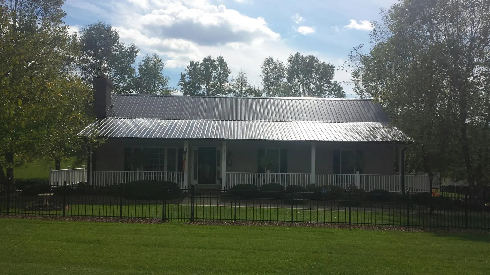 Gray metal roof on a brick ranch with a full width front porch — Gutter Guard Installation work by our crew in Herminie