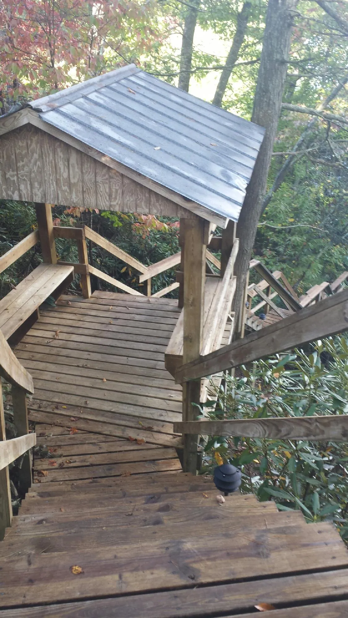 Metal roofed shelter over wooden steps on a wooded walkway — Skylight Repair & Installation work by our crew in Herminie