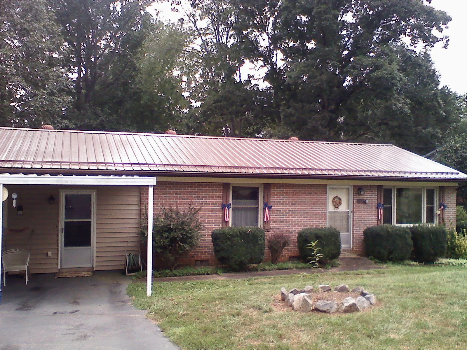Bronze metal roof and carport on a brick ranch home — Roof Repair work by our crew in Herminie