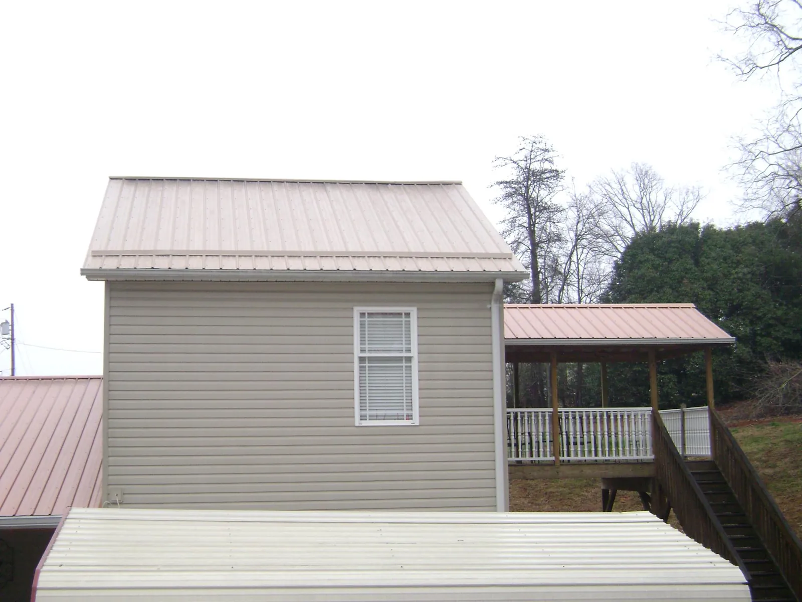 Tan metal roofs on a two story addition and attached porch, from a Roof Replacement job in Herminie