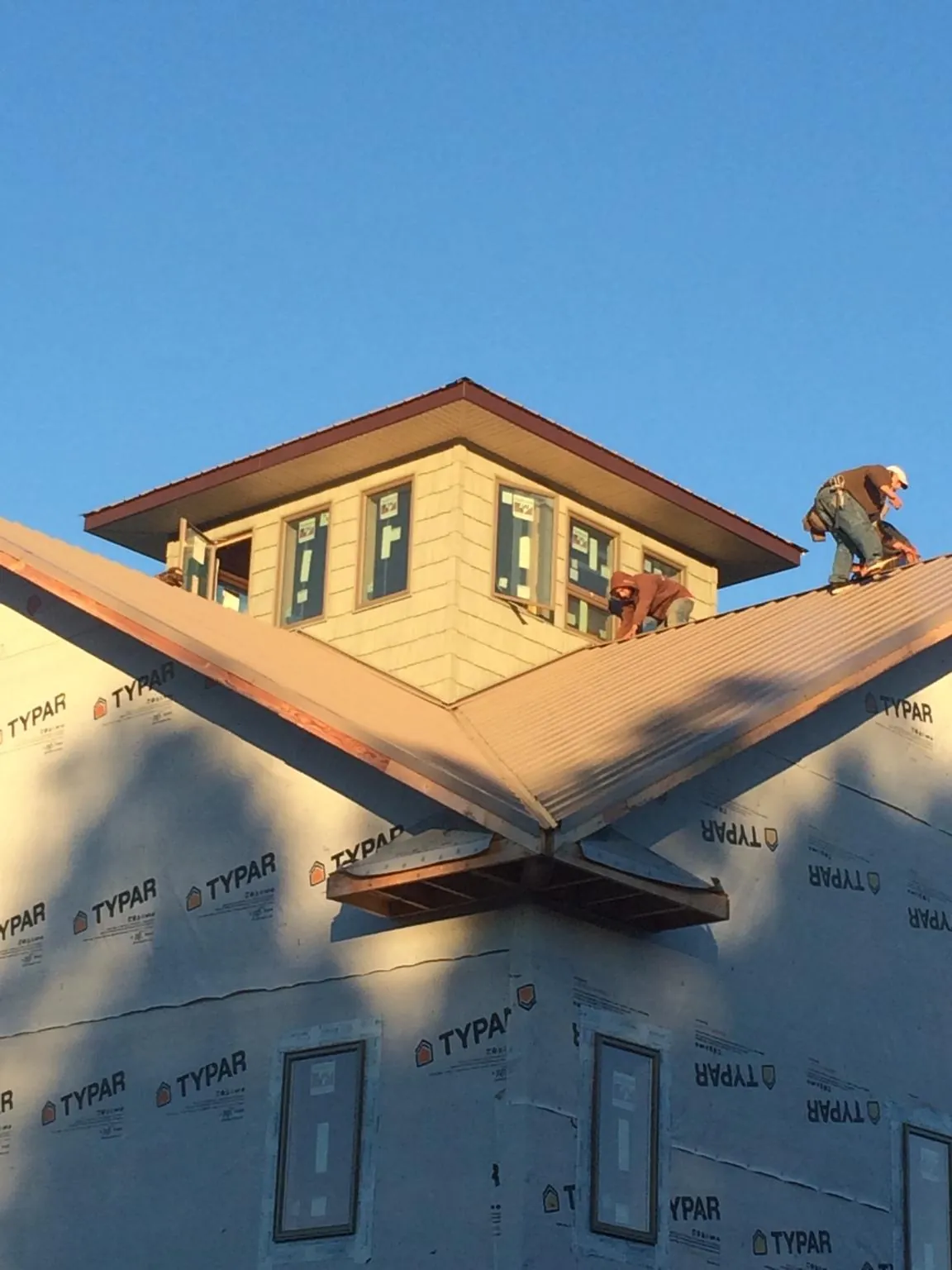 Roofers working around a rooftop cupola on a new metal roof at sunset — Roof Waterproofing in Herminie by Roofing Brothers